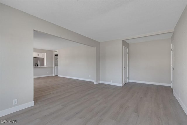 spare room with baseboards and wood finished floors