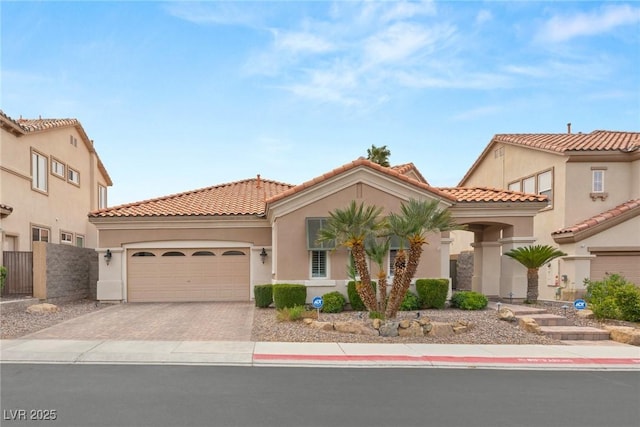 mediterranean / spanish-style home featuring stucco siding, fence, an attached garage, a tiled roof, and driveway