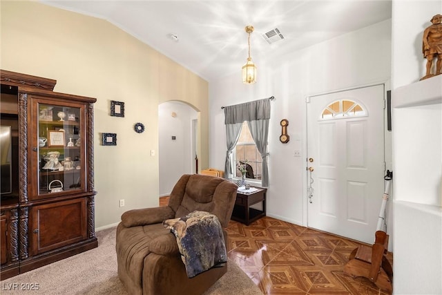 foyer with arched walkways, baseboards, lofted ceiling, and visible vents