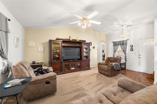 living area with visible vents, a ceiling fan, arched walkways, and vaulted ceiling