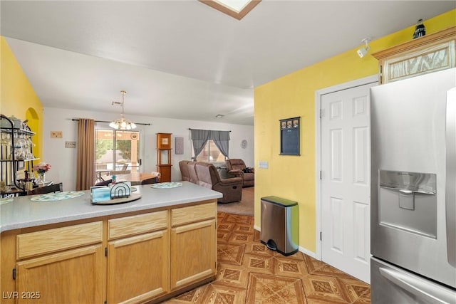 kitchen with stainless steel fridge with ice dispenser, an inviting chandelier, light countertops, open floor plan, and decorative light fixtures