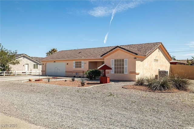 ranch-style house with an attached garage, a tile roof, fence, stucco siding, and driveway