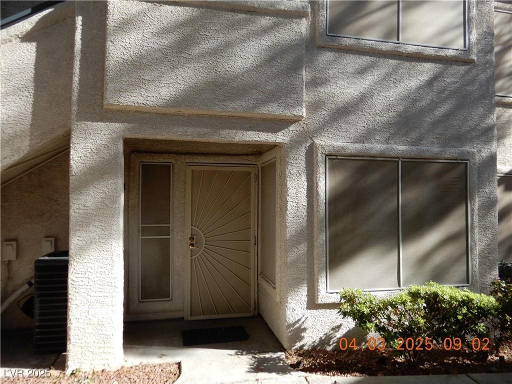 3051 Key Largo Dr Unit 103, Las Vegas, NV 89120 - view of exterior entry with stucco siding and central AC unit