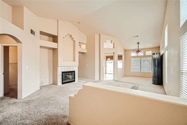 9532 Calico Garden Ave, Las Vegas, NV 89134 - unfurnished living room with light carpet, ceiling fan, a fireplace, lofted ceiling, and arched walkways
