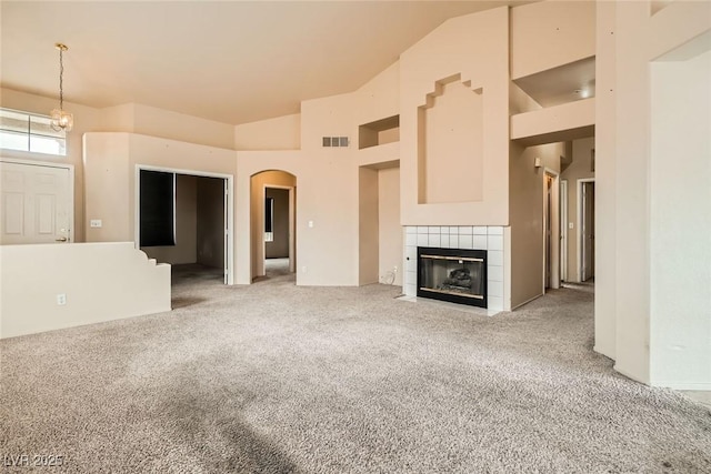 9532 Calico Garden Ave, Las Vegas, NV 89134 - unfurnished living room featuring carpet floors, arched walkways, a fireplace, high vaulted ceiling, and a chandelier