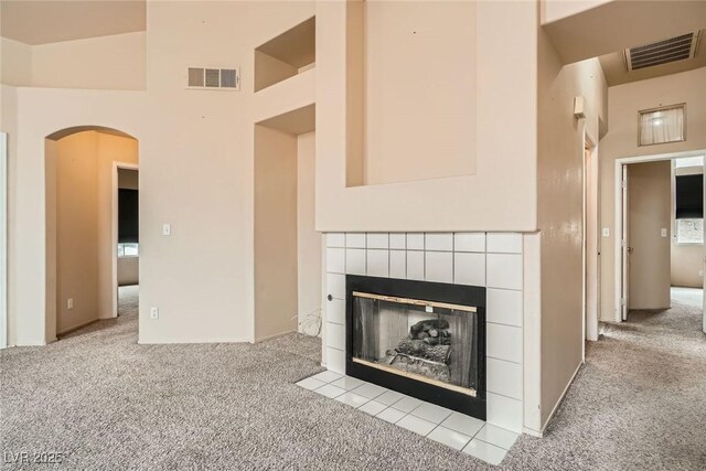 9532 Calico Garden Ave, Las Vegas, NV 89134 - unfurnished living room featuring carpet, a tile fireplace, arched walkways, a high ceiling, and baseboards