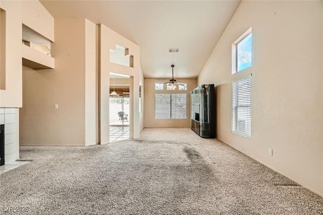 9532 Calico Garden Ave, Las Vegas, NV 89134 - unfurnished living room featuring plenty of natural light, light carpet, a tile fireplace, a ceiling fan, and high vaulted ceiling