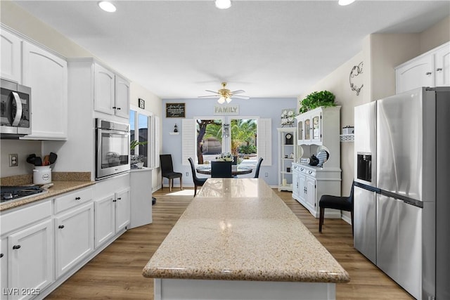 2606 Crested Butte St, Henderson, NV 89052 - kitchen featuring a kitchen island, a ceiling fan, appliances with stainless steel finishes, light stone counters, and white cabinetry