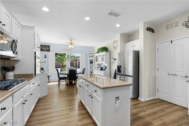 2606 Crested Butte St, Henderson, NV 89052 - kitchen featuring ceiling fan, light wood-style floors, stainless steel appliances, a kitchen island, and visible vents