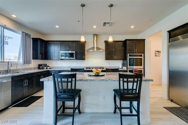 8637 Home Gate Ct, Las Vegas, NV 89113 - kitchen with wall chimney range hood, appliances with stainless steel finishes, a sink, a kitchen bar, and recessed lighting