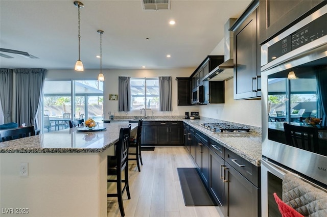 8637 Home Gate Ct, Las Vegas, NV 89113 - kitchen featuring a breakfast bar, a kitchen island, recessed lighting, light stone countertops, and light wood-style flooring