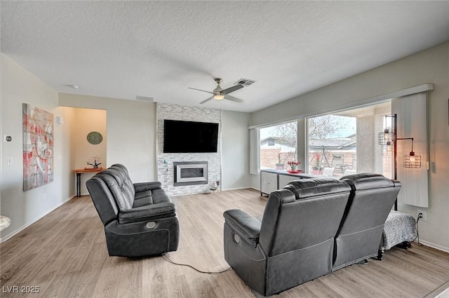 7460 Chaffinch St, North Las Vegas, NV 89084 - living area with wood finished floors, ceiling fan, a large fireplace, a textured ceiling, and baseboards