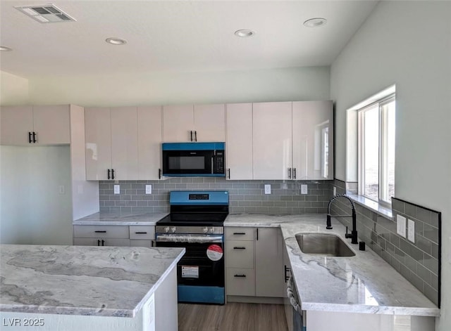 kitchen featuring light wood-type flooring, a sink, stainless steel range with electric cooktop, visible vents, and black microwave