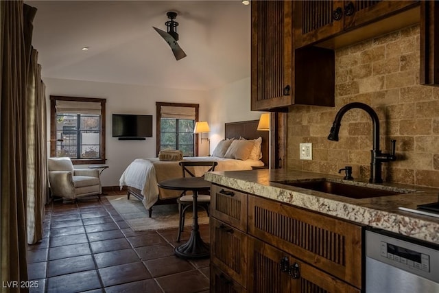 kitchen with a sink, stainless steel dishwasher, backsplash, open floor plan, and dark tile patterned floors