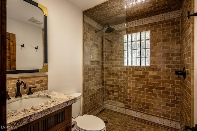 bathroom featuring a tile shower, toilet, and vanity