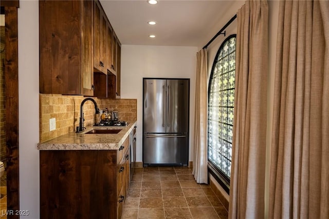 kitchen featuring stainless steel appliances, a sink, tasteful backsplash, recessed lighting, and light stone counters
