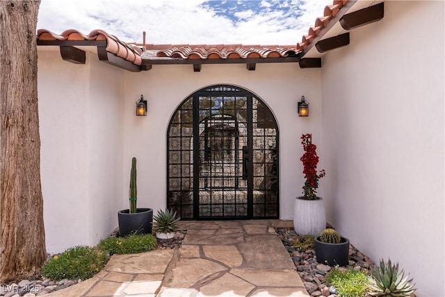 doorway to property featuring a tile roof and stucco siding