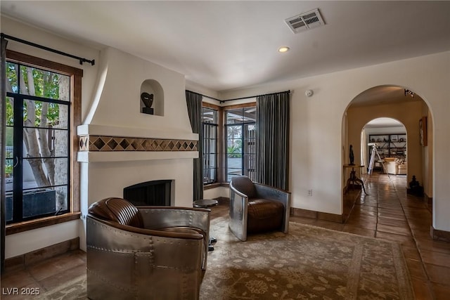 sitting room featuring arched walkways, baseboards, tile patterned floors, recessed lighting, and a fireplace