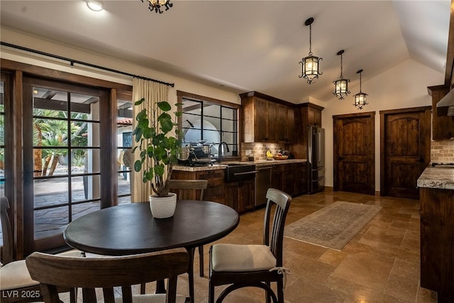 dining room featuring light stone finish flooring and vaulted ceiling