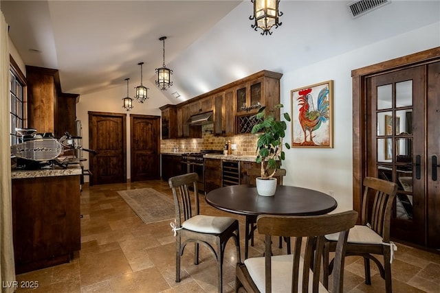 dining room featuring stone finish flooring and lofted ceiling