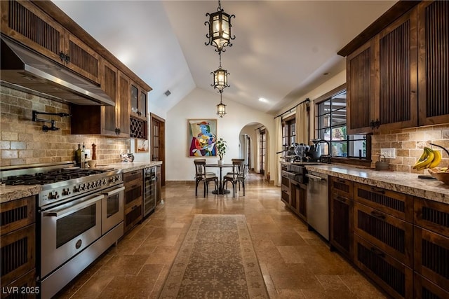 kitchen featuring stainless steel appliances, arched walkways, hanging light fixtures, backsplash, and lofted ceiling