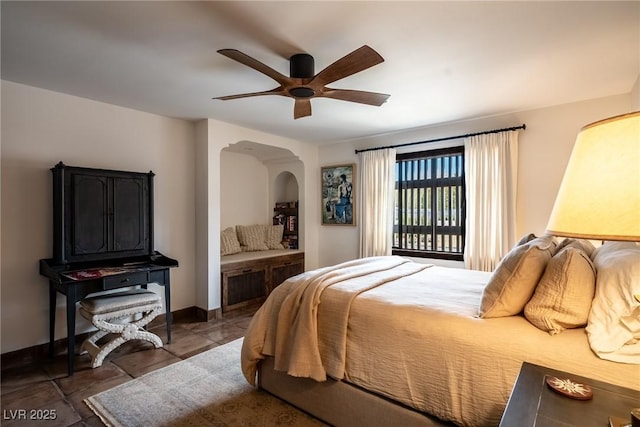 bedroom with arched walkways, tile patterned floors, baseboards, and a ceiling fan