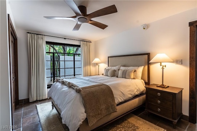 bedroom featuring ceiling fan, baseboards, and dark tile patterned flooring