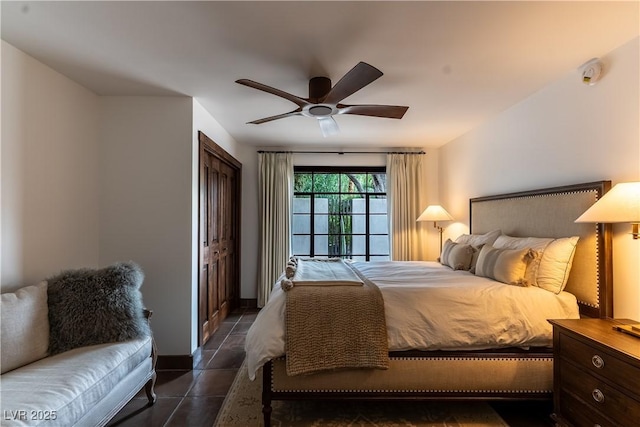 bedroom with dark tile patterned flooring, a ceiling fan, a closet, and baseboards
