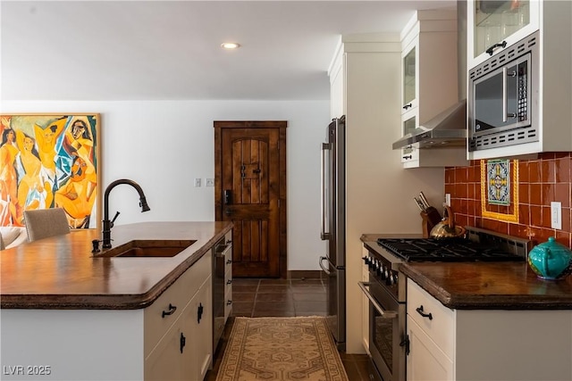 kitchen with premium appliances, a sink, range hood, dark countertops, and recessed lighting