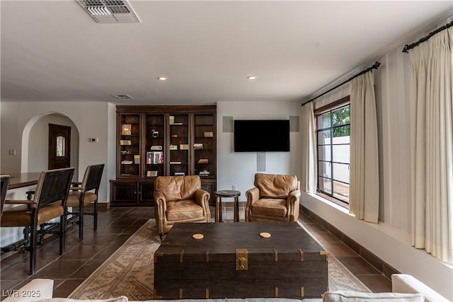 living room with dark tile patterned floors, arched walkways, recessed lighting, and baseboards