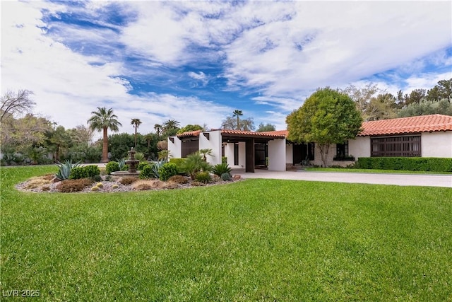 view of front of home with stucco siding, a front lawn, concrete driveway, and a tiled roof