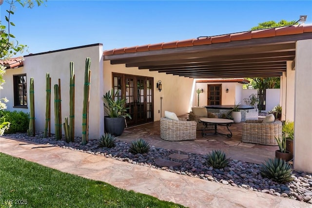 rear view of property with a patio, french doors, and stucco siding