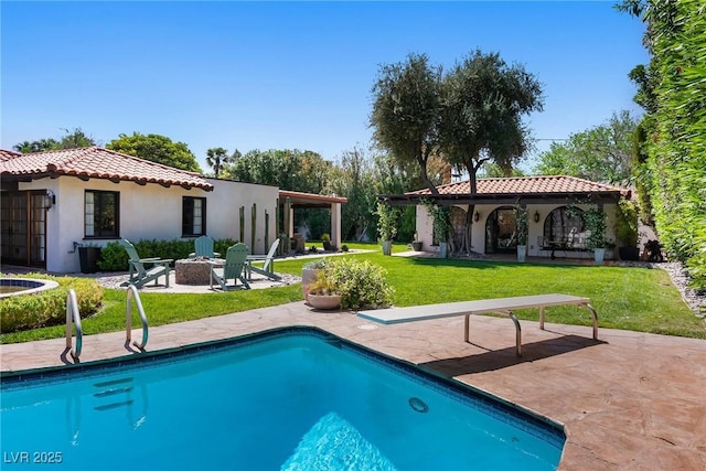 back of house featuring an outdoor fire pit, a patio, a tile roof, stucco siding, and an outdoor pool