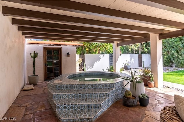 view of patio with an in-ground hot tub and fence