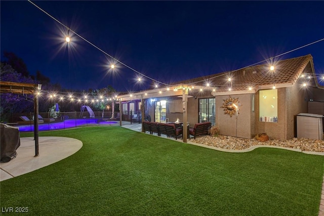 yard at night with an outdoor living space, an outdoor pool, and a patio area