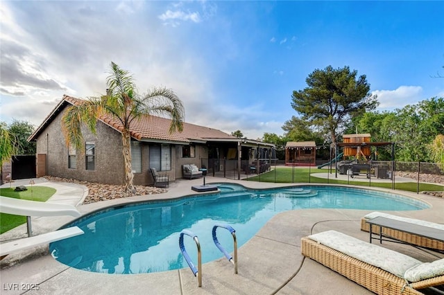 view of swimming pool with a water slide, a patio area, fence, a playground, and a fenced in pool