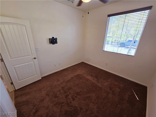 unfurnished room with dark colored carpet, a ceiling fan, and baseboards