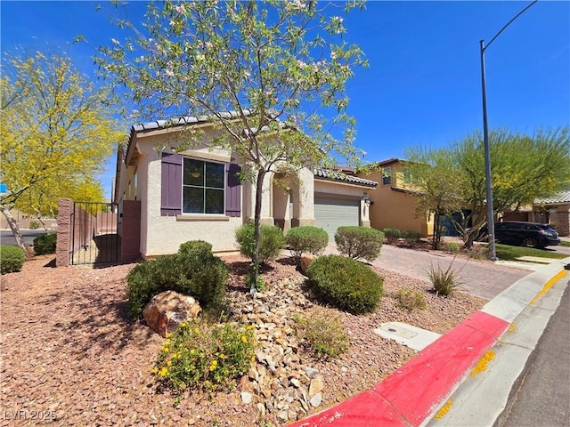 view of front of property with a gate, an attached garage, driveway, and stucco siding