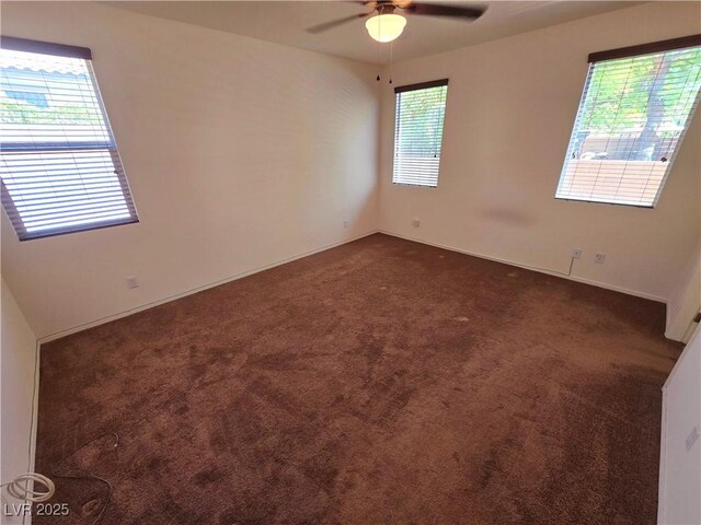 empty room featuring ceiling fan, baseboards, and dark colored carpet