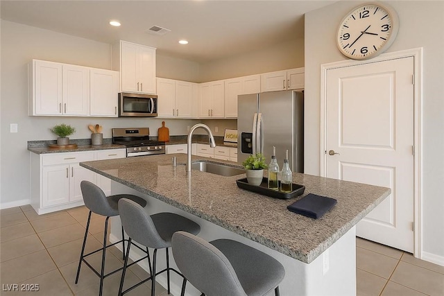 9871 Magnus Ct, Las Vegas, NV 89178 - kitchen featuring stainless steel appliances, light tile patterned flooring, a sink, white cabinetry, and a kitchen bar