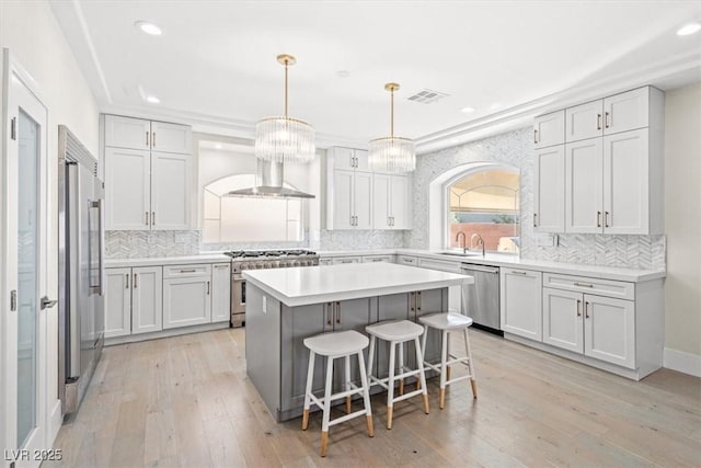 6335 Mount Eden Ave, Las Vegas, NV 89139 - kitchen featuring appliances with stainless steel finishes, a breakfast bar area, decorative backsplash, wall chimney exhaust hood, and recessed lighting