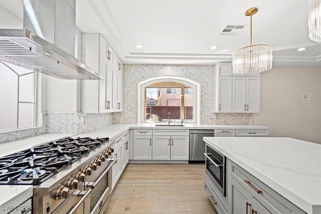 6335 Mount Eden Ave, Las Vegas, NV 89139 - kitchen with stainless steel appliances, wall chimney exhaust hood, a raised ceiling, recessed lighting, and light wood finished floors