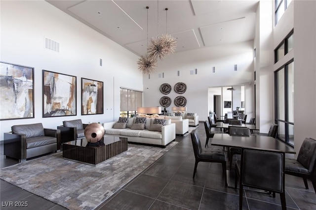 living area with visible vents, a high ceiling, and a healthy amount of sunlight