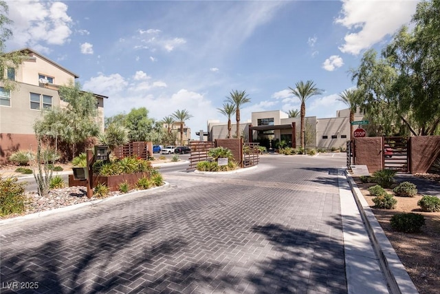 view of road featuring traffic signs, a gated entry, and curbs
