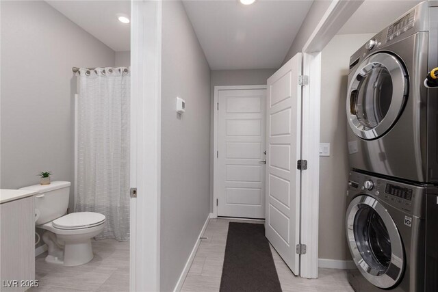 clothes washing area with baseboards, laundry area, and stacked washer / drying machine