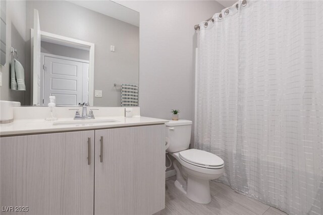 bathroom featuring toilet, vanity, and curtained shower