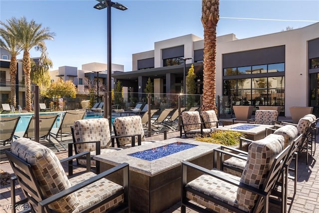 view of patio featuring a community pool, a fire pit, and fence