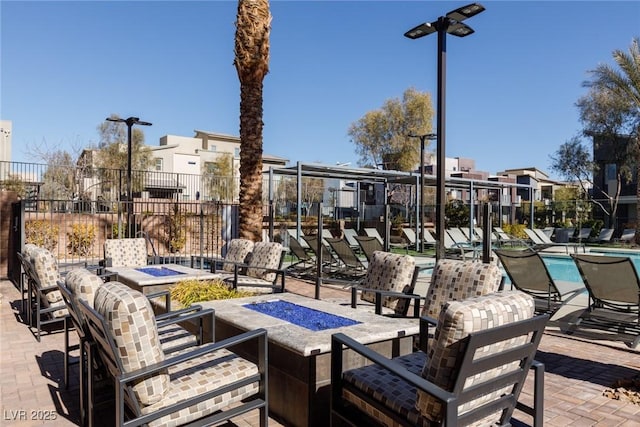 view of patio / terrace featuring a community pool, a fire pit, and fence