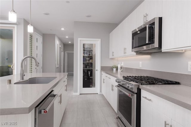 kitchen featuring a sink, light countertops, appliances with stainless steel finishes, and pendant lighting
