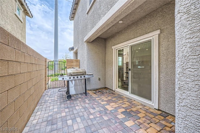 view of patio featuring grilling area, fence, and a gate